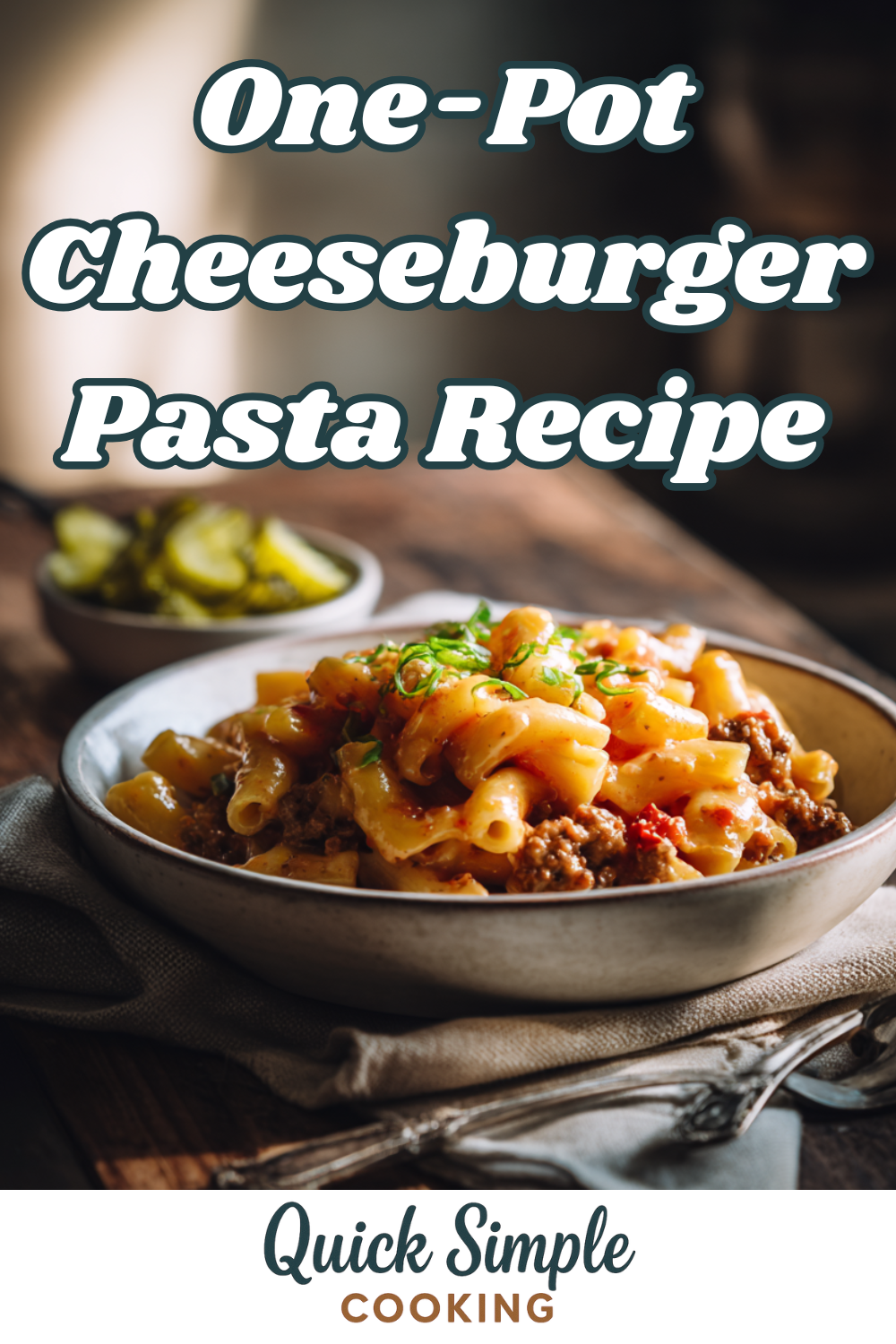 A bowl of one-pot cheeseburger pasta topped with herbs sits on a table, with a side of pickles and a napkin nearby. Text reads: One-Pot Cheeseburger Pasta Recipe.